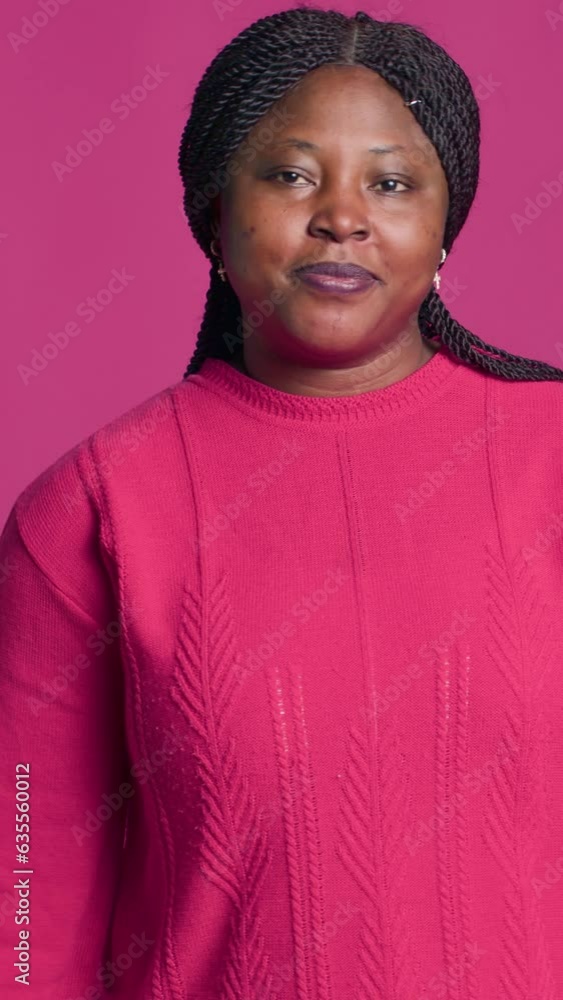 vertical video Expressive young black woman showing time-out sign using her hands in front of pink background. African american beauty displaying pause-break signal with body language towards camera. vertical video Expressive young black woman showing time-out sign using her hands in front of pink background. African american beauty displaying pause-break signal with body language towards camera.