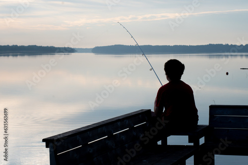 Boy Fishing from Dock in Morning sunrise silhouette