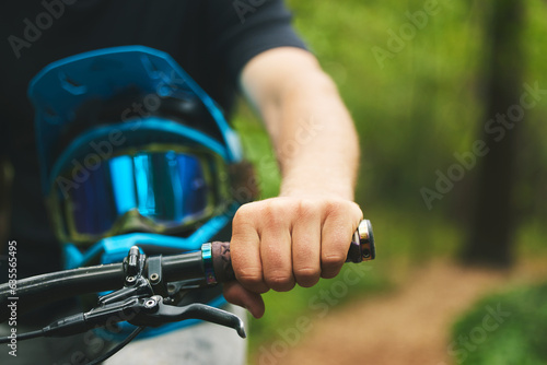 Hand, handle and cycling with helmet, sports and person in forest, mockup space and closeup. Mountain bike, biker outdoor and travel with adventure, fitness and ready to ride, exercise and training
