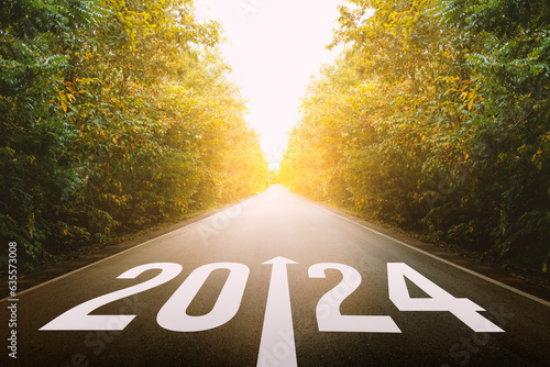 The new year 2024 or straightforward concept. Text 2024 written on the road in the middle of asphalt road at sunset. planning and challenge, business strategy, opportunity, hope, and new life.