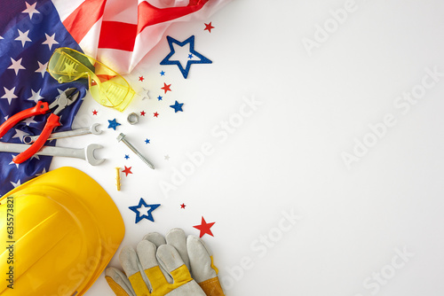 Join the celebration american Labor Day. Top view arrangement of american flag, construction hard hat, tools, goggles, gloves, event confetti on white background with empty space for promo or text photo