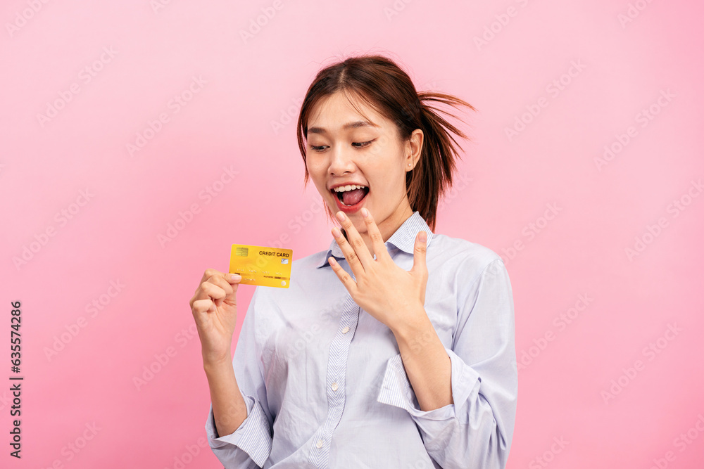 Young asian woman holding credit card and raising one hand to covering mouth while feeling surprised Young asian woman holding credit card and raising one hand to covering mouth while feeling surprised