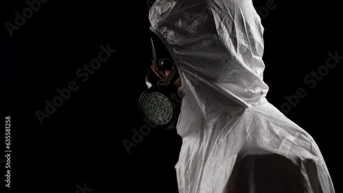 Laboratory worker in a chemical protection suit, panting, raises his head