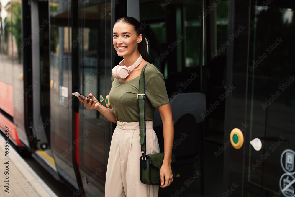 Joyful Passenger Young Lady Exiting Tram, Texting on Phone - obrazy, fototapety, plakaty 