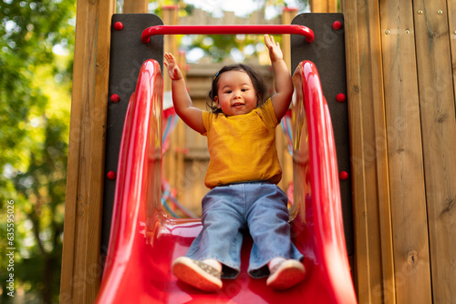 Chinese Toddler Infant Girl Enjoying Playground Fun, Riding Slide Outdoors