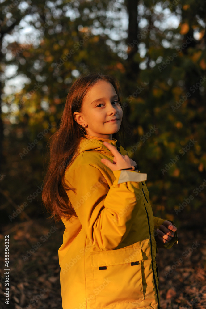 A beautiful caucasian girl dressed in a yellow jacket and with loose hair walks in the forest in late autumn A beautiful caucasian girl dressed in a yellow jacket and with loose hair walks in the forest in late autumn