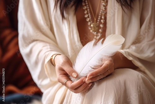 Woman with boho jewellery holding a feather in her hands close up