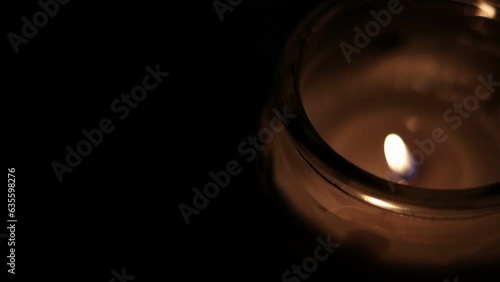 Closeup Of Flickering Candle Flame In Transparent Jar - High Angle Shot. Close-up of the flame burning on candle, isolated on a black background. Candle flame in dark