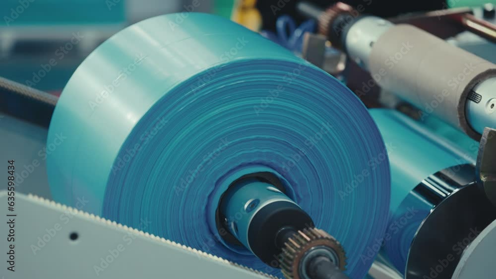 Factory Winds Roll of Polyethylene into Fabric, Producing Colored Polyethylene Plastic Garbage Bag. Factory Winds Roll of Polyethylene into Fabric, Producing Colored Polyethylene Plastic Garbage Bag.