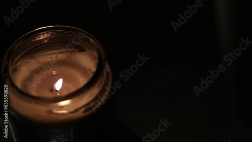 Closeup Of Flickering Candle Flame In Transparent Jar - High Angle Shot. Close-up of the flame burning on candle, isolated on a black background. Candle flame in dark