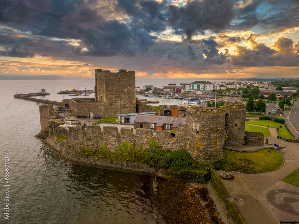 Aerial view of medieval Anglo Norman Carrickfergus castle with large rectangular keep dramatic sunset sky