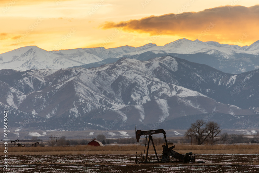 Pump jack in field in front of mountains