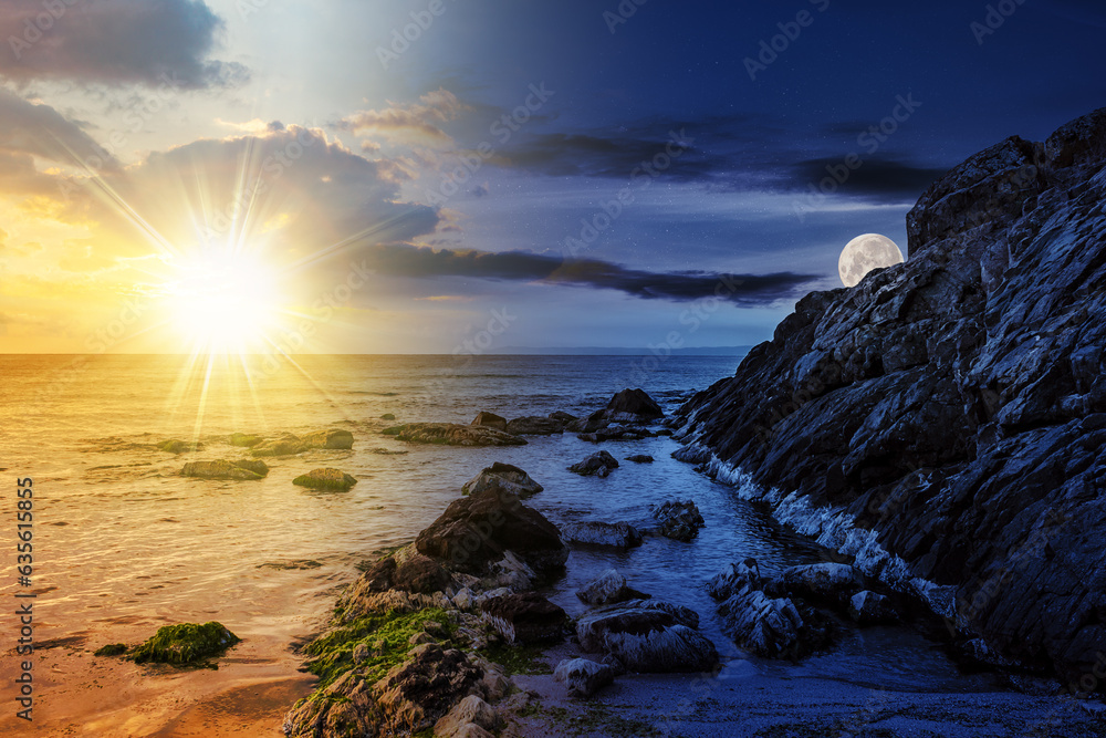 Obraz premium large boulders and seaweed on the rocky coast of the sea with sun and moon at twilight. day and night time change concept. mysterious countryside scenery in morning light