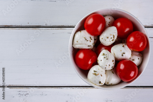 buffalo mozzarella balls and cherry tomatoes in white bowl photo