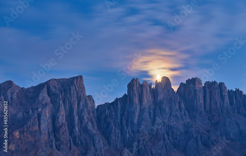 Night photo of Mount Latemar, the moon rises over the mountain range of Bolzano province, Italy