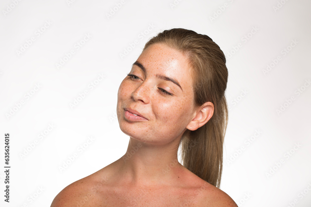Pretty girl with freckles looks away with her hair tied up in front of the camera on a white background Pretty girl with freckles looks away with her hair tied up in front of the camera on a white background