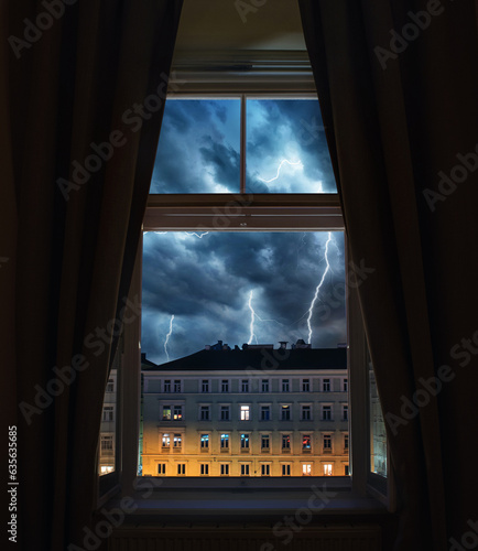 Window view of sparkling lightning in the old town. Concept on the theme of weather, natural disasters, apocalypse, etc. photo
