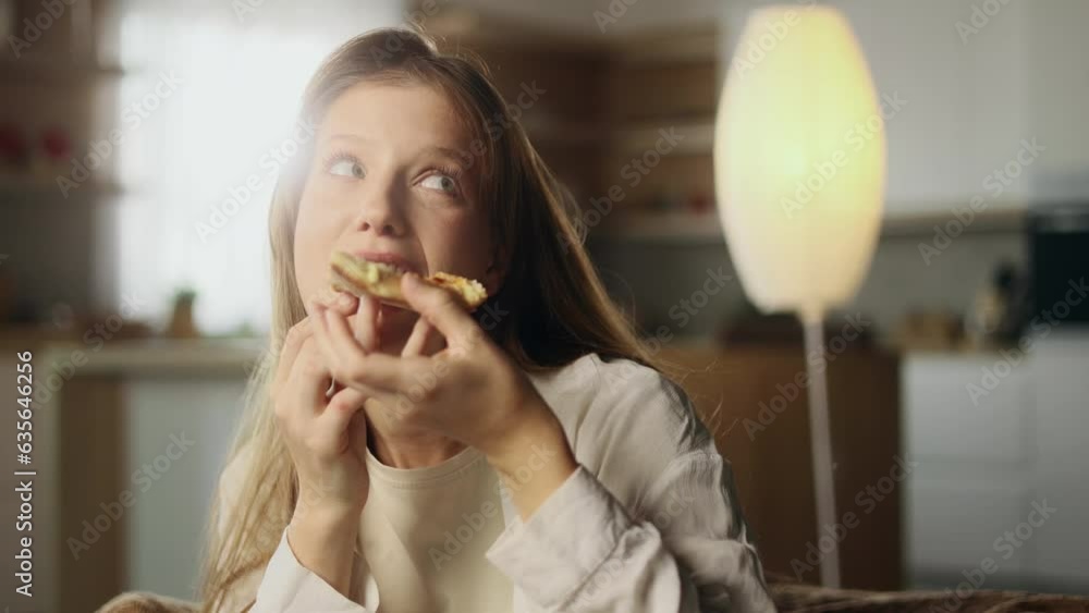 Portrait of pretty young woman looking around to make sure nobody watching eating pizza with great pleasure and enjoying beautiful day at home Break the diet or excellent food concept