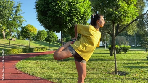 Active multiracial young woman engages in revitalizing morning exercising in golden sunlight of new day. She stretches warms up legs, preparing for invigorating workout in public park at daybreak
