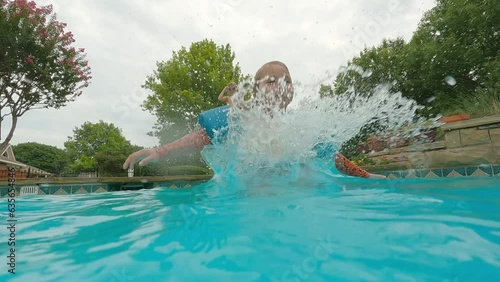 Cute 4 year old girl with pool floaties jumps in deep end, opens eyes underwater