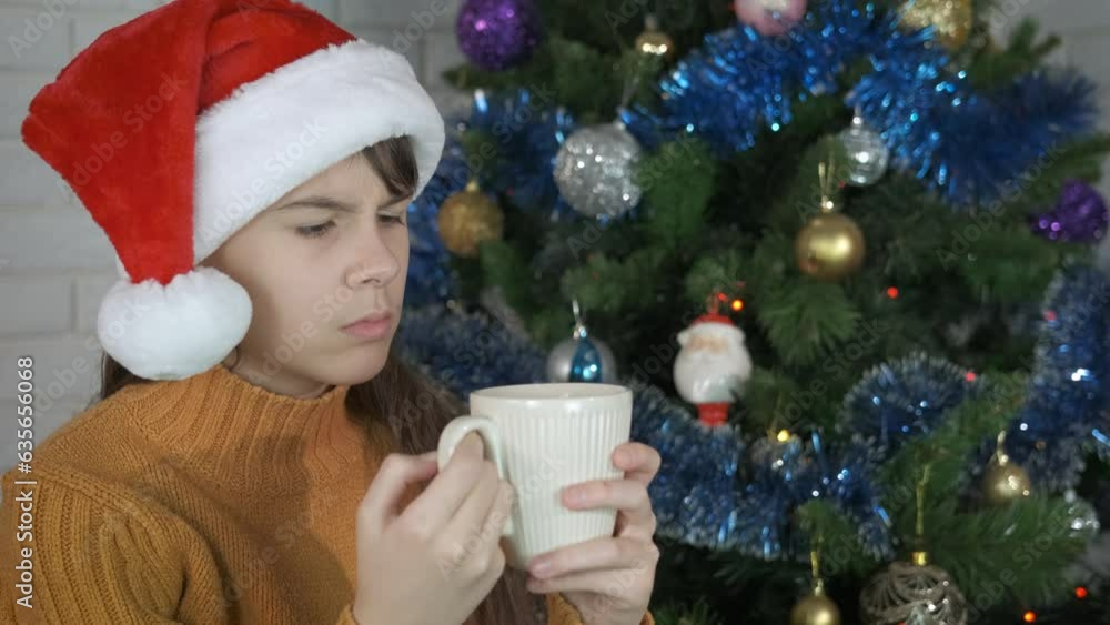 Girl drinking hot milk by Christmas tree. A young girl enjoy hot tea by the Christmas tree. A concept of depression during winter holidays. Girl drinking hot milk by Christmas tree. A young girl enjoy hot tea by the Christmas tree. A concept of depression during winter holidays.