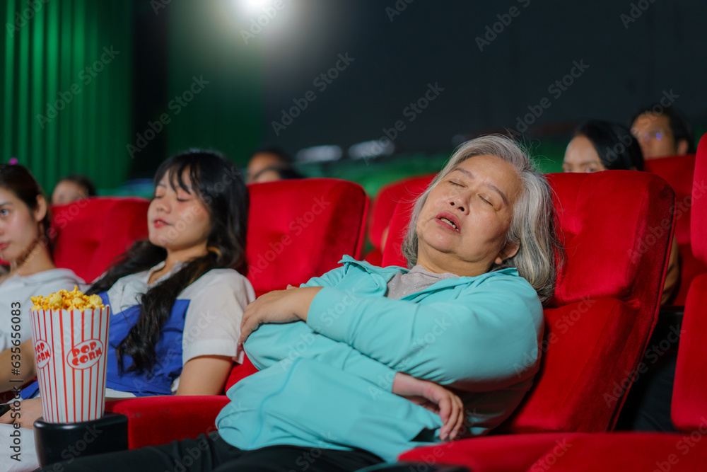 Asian elderly women sleep while watching movies in the cinema, representing the monotony of watching movies.. Asian elderly women sleep while watching movies in the cinema, representing the monotony of watching movies..