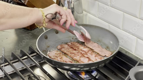 Turning bacon over in a frying pan.