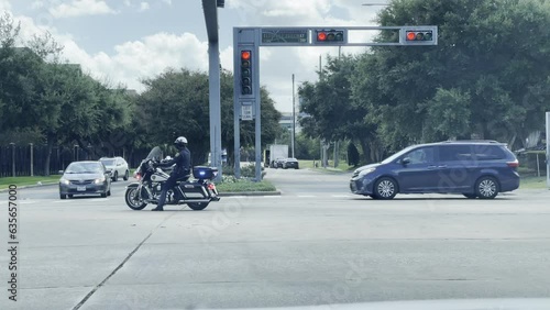 A police officer is directing traffic to allow for a funeral procession to move through an intersection.