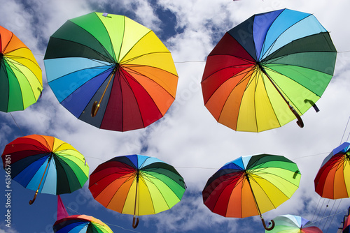 several colorful parasols hanging on a sunny day