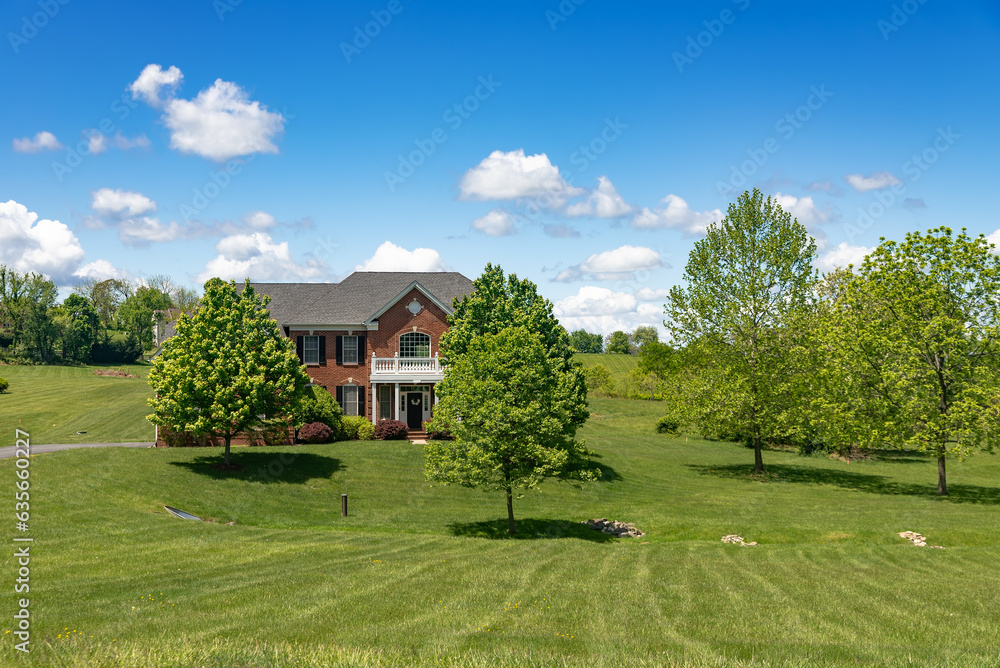 large country house in the English style with a large mowed lawn in front of the entrance.