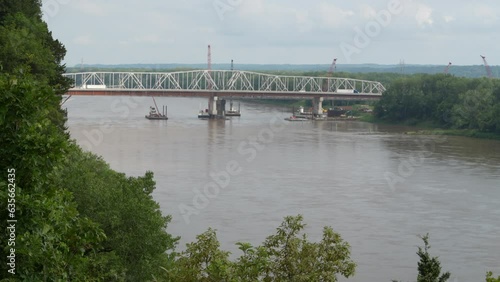 traffic on a newly constructed bridge over Missouri River at Rocheport, MO with barges, construction equipment and old bridge behind photo