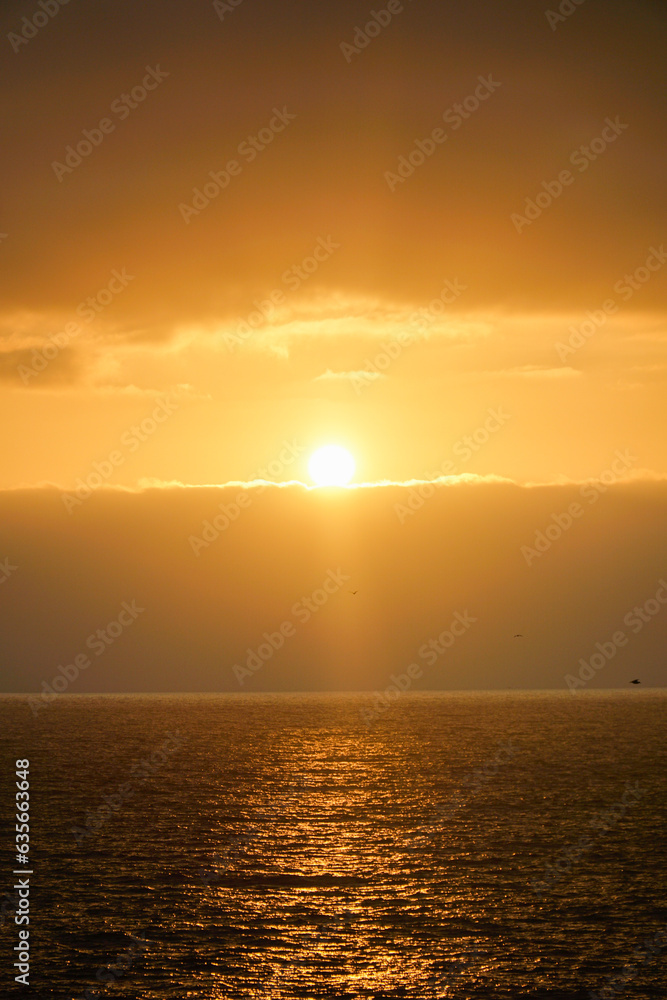 Vertical shot capturing the serene beauty of a golden orange sunset over the sea in Viña del Mar, creating a captivating and tranquil ambiance.