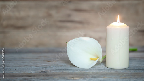 Foto CALLA FLOWER AND A LIGHTED CANDLE ON WOOD BACKGROUND