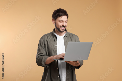 Happy man with laptop on beige background