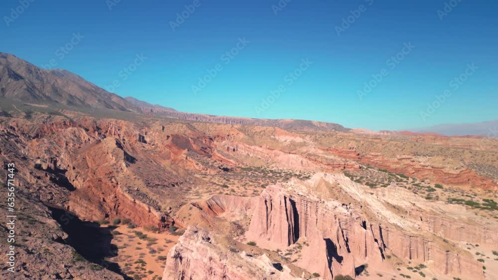 Aerial view drone flying over scenic red rocky mountains and arid desert landscape with a clear blue sky. Aerial view drone flying over scenic red rocky mountains and arid desert landscape with a clear blue sky.