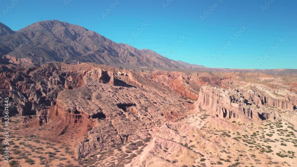 Aerial view drone flying over scenic red rocky mountains and arid desert landscape with a clear blue sky. Aerial view drone flying over scenic red rocky mountains and arid desert landscape with a clear blue sky.
