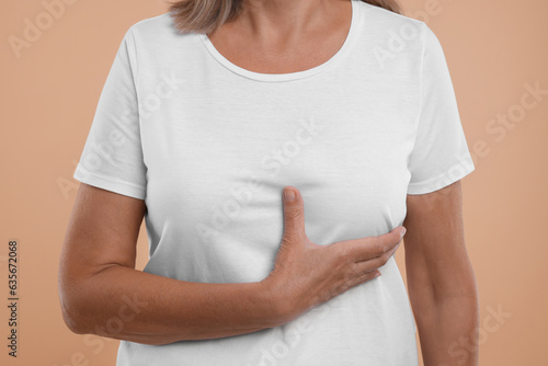 Woman doing breast self-examination on light brown background, closeup © New Africa