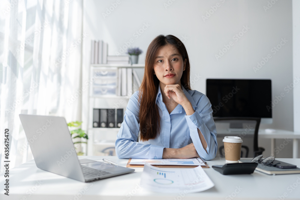 Asian businesswoman sitting and thinking analyze financial reports Business growth using laptop computer and documents, graphs, charts, investment calculators. Office business plan Asian businesswoman sitting and thinking analyze financial reports Business growth using laptop computer and documents, graphs, charts, investment calculators. Office business plan
