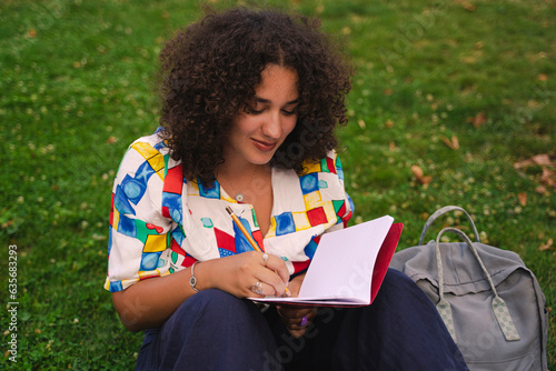 Young female student writing outdoors