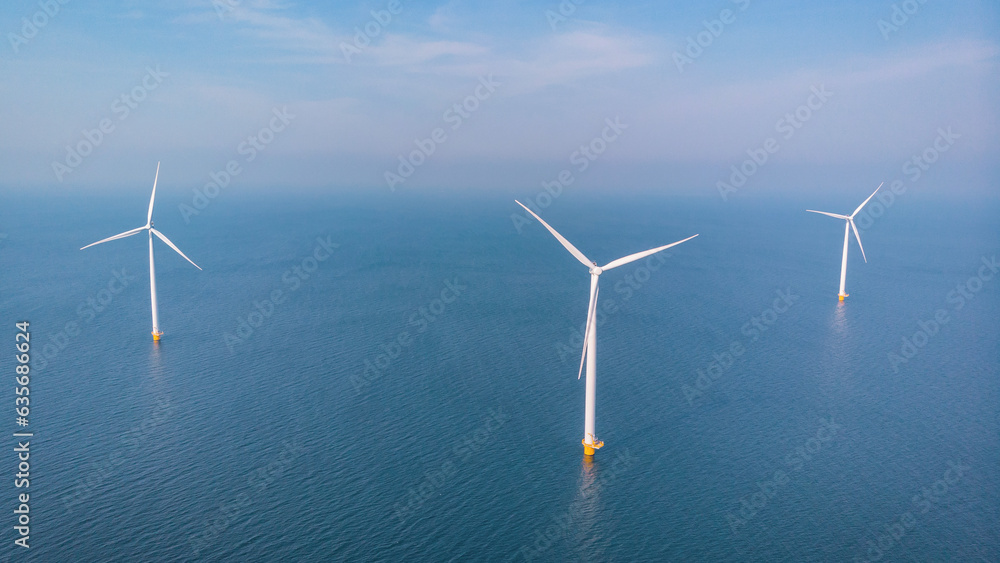Wind mill turbines park with clouds and a blue sky, windmill park in the ocean aerial view with wind turbine Flevoland Netherlands Ijsselmeer. Green Energy production in the Netherlands Wind mill turbines park with clouds and a blue sky, windmill park in the ocean aerial view with wind turbine Flevoland Netherlands Ijsselmeer. Green Energy production in the Netherlands