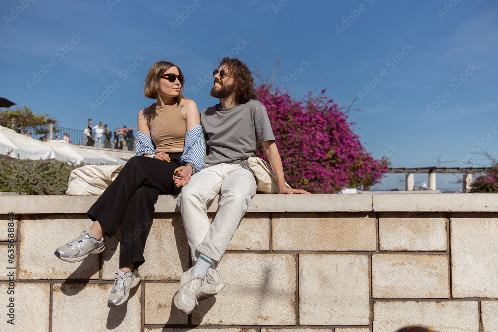 Smiling tourist couple sitting outside on old city street and looking each other. High quality photo