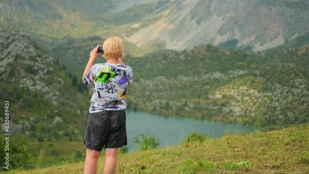 Tourist shoots on phone scenic views, make video grandiose mountain landscape with lake. Woman blonde standing on top of mountain during a tourist trip. Nature's grandeur in Asia's. Tourist shoots on phone scenic views, make video grandiose mountain landscape with lake. Woman blonde standing on top of mountain during a tourist trip. Nature's grandeur in Asia's.