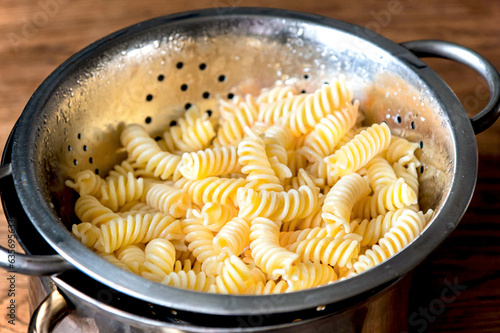 Fusilli pasta in a stainless steel colander on background. photo