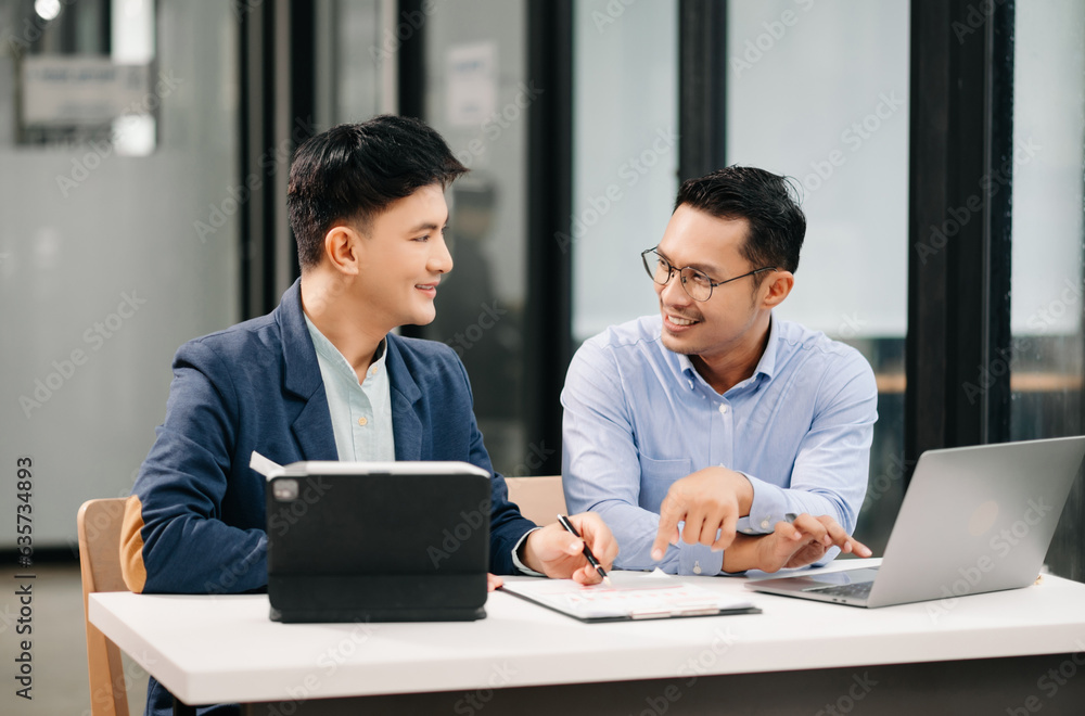 Two Asian business workers talking on the smartphone, tablet and using laptop at the office. Two Asian business workers talking on the smartphone, tablet and using laptop at the office.