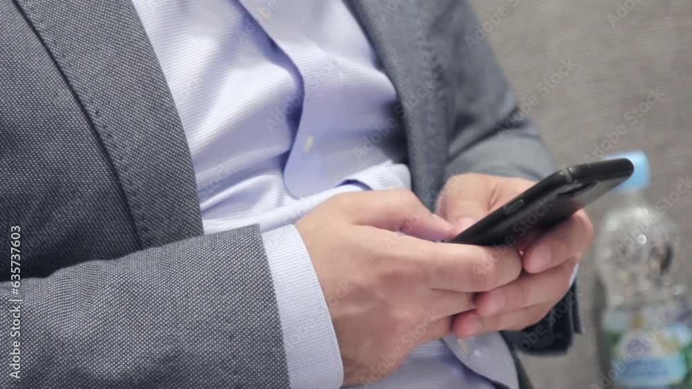 Man sitting on a chair in his jacket is typing something in the phone Man sitting on a chair in his jacket is typing something in the phone