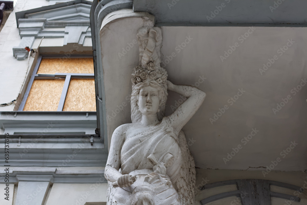 Support for a balcony in the form of a Greek statue. Windows sewn with wood after shelling