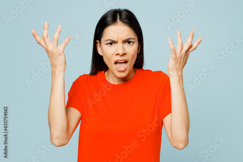 Young displeased sad mad latin woman wear orange red t-shirt casual clothes spead hands scream shout look camera isolated on plain pastel light blue cyan background studio portrait. Lifestyle concept. photo