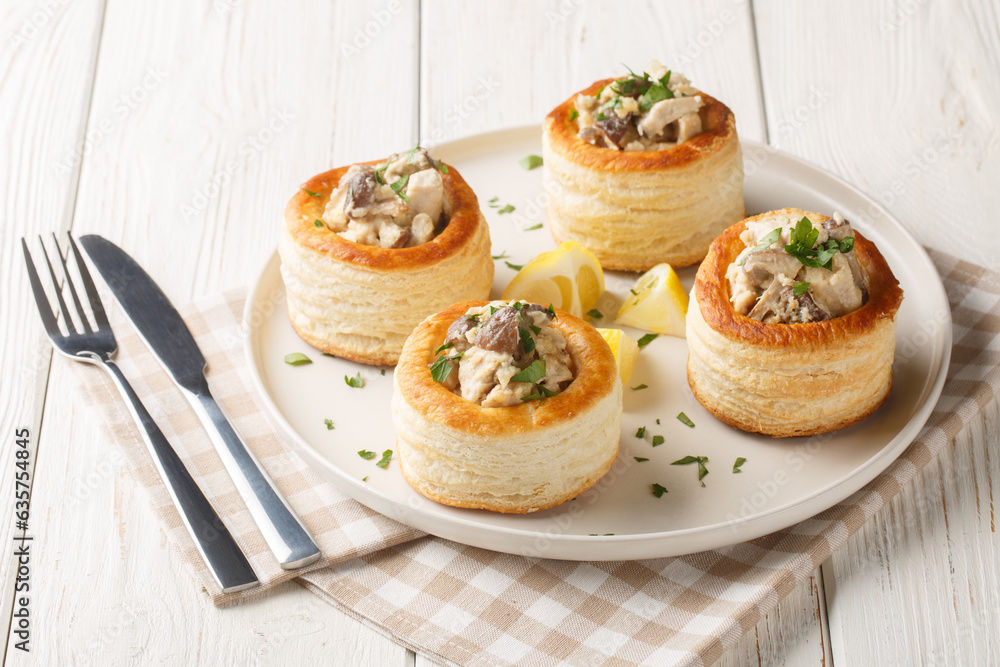 Vol-au-Vent is a hollow puff pastry shell filled with a creamy mushroom and chicken filling closeup on the plate on the white wooden table. Horizontal Vol-au-Vent is a hollow puff pastry shell filled with a creamy mushroom and chicken filling closeup on the plate on the white wooden table. Horizontal
