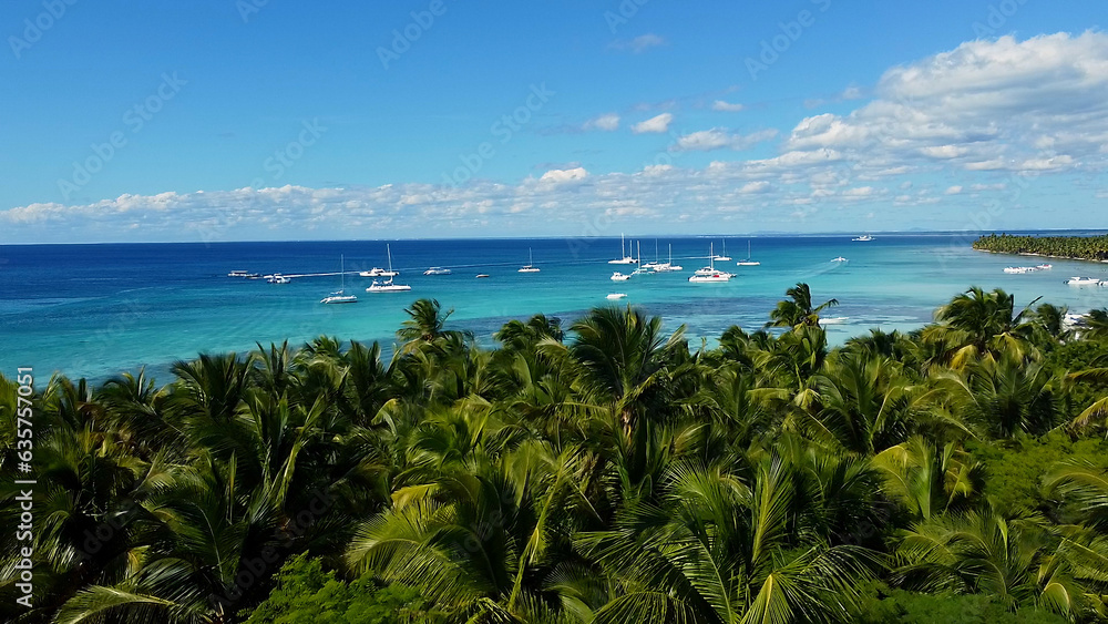 Aerial view of the yachts moored in beautiful lagoon with turquoise sea water on the shore of a wild tropical beach with palm trees and white sand