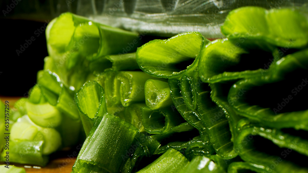 Slicing, cooking process, tasty and bright image, sharp knife, slicing green onions, dark background on the background. Slicing, cooking process, tasty and bright image, sharp knife, slicing green onions, dark background on the background.